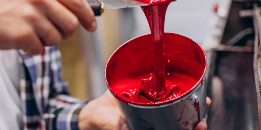 Personal manipulando con una espatula una pintura roja con regulador de PH